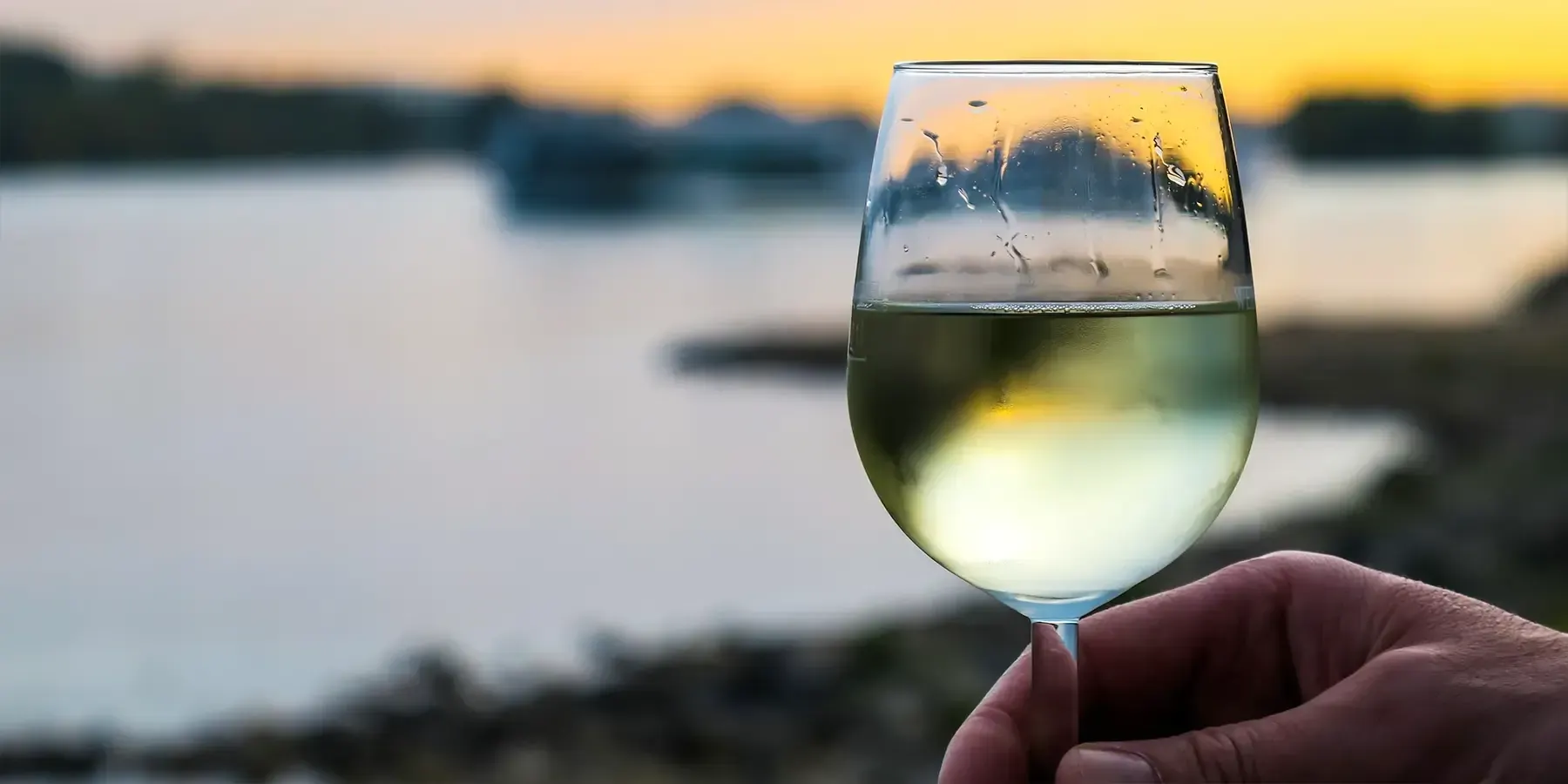 Un verre de vin blanc frais devant le couché du soleil