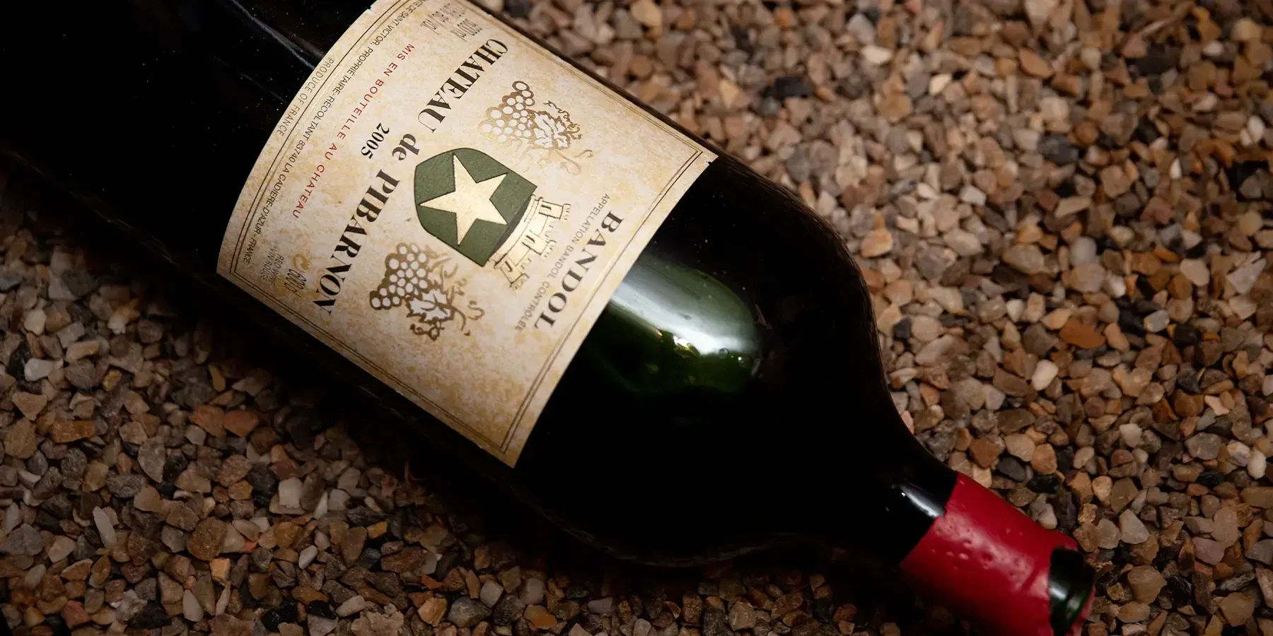 Une bouteille de Château de Pibarnon 2005 couchée sur des cailloux