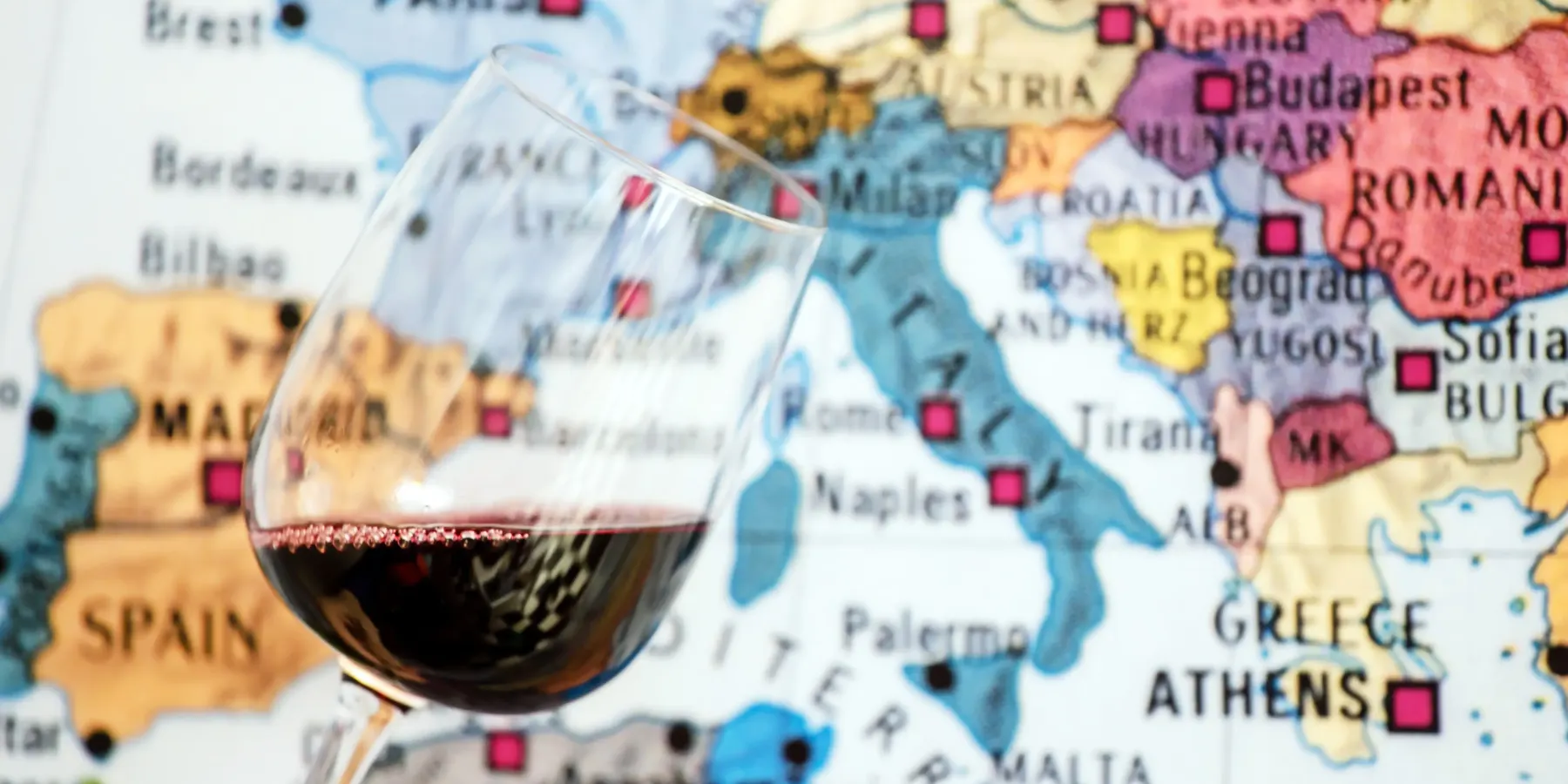 Verre de vin rouge devant une carte du monde